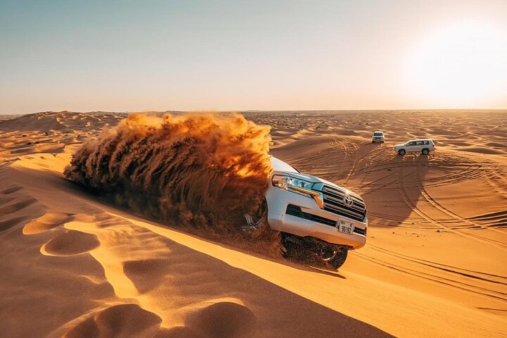 Experience the excitement of dune bashing across stunning red dunes capturing unforgettable moments in the desert's golden sands and enjoying traditional camel rides for a unique cultural connection.